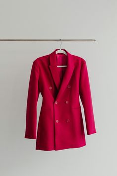 a bright pink jacket hanging on a clothesline with a hanger in the background