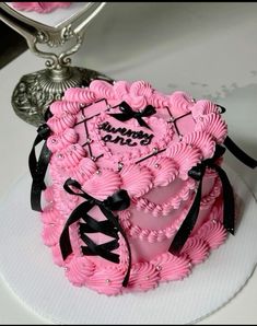 a pink cake with black ribbon on top