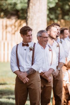 a group of men standing next to each other wearing brown suspenders and bow ties