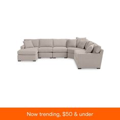 a large sectional couch with pillows on the top and bottom, sitting in front of an orange background