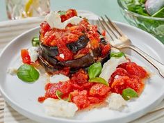 a white plate topped with stuffed eggplant covered in marinara sauce and cheese