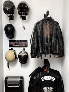 motorcycle helmets and leather jackets are hanging on the wall next to a motorcyclist's jacket