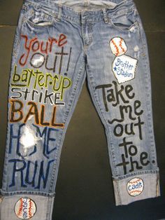 a pair of jeans with words written on them and baseball balls painted on the back