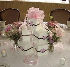 the table is decorated with pink flowers and white boxes