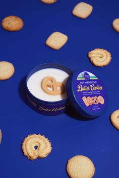 some cookies are next to a jar of buttery cookie flavored crackers on a blue surface