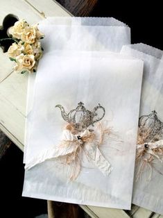 three napkins with crowns on them sitting next to flowers