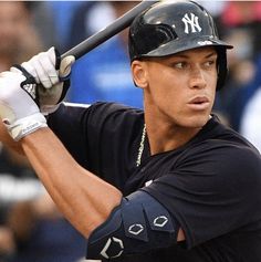 a baseball player holding a bat in front of a crowd and wearing a black shirt