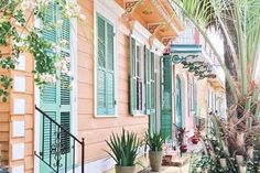 an orange house with green shutters and palm trees on the side walk in front of it