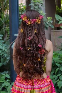 the back of a woman's head with flowers in her hair and braids