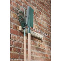 there is a green rake on the side of a brick building with a metal rack attached to it