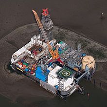 an aerial view of a drilling rig with a clock on the front and side of it