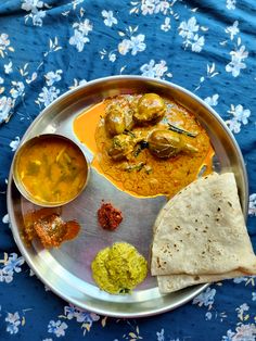 a metal plate topped with food on top of a blue tablecloth covered table cloth