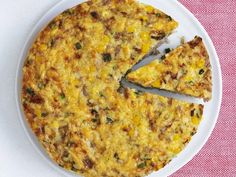 a cheese and vegetable quiche on a white plate with a slice missing from it