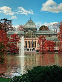 a large building with a fountain in front of it and lots of trees around it