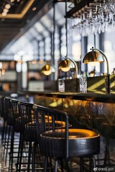 an empty bar with several stools and lights hanging from the ceiling in front of it