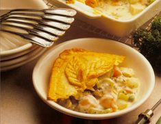 a bowl filled with food next to a fork and some broccoli on a table