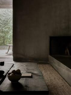 a bowl of fruit sitting on top of a wooden table next to a fire place