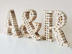 the word art made out of wine corks sits on a white surface next to a pile of wood