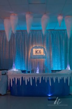 an ice and snow themed wedding reception with blue lights, white drapes and icing on the walls