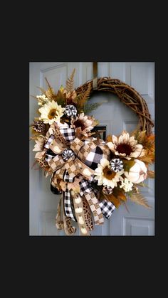 a wreath with sunflowers and plaid ribbon hanging on the front door for fall