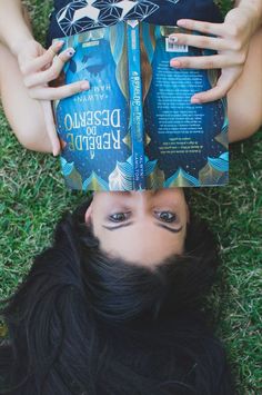 a person laying on the grass with a book over their head and hands above their head