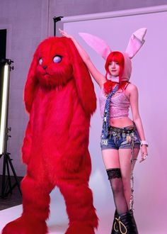 a woman standing next to a giant red bunny