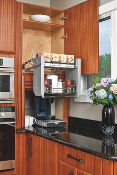 a kitchen with wooden cabinets and black counter tops, along with a vase filled with flowers