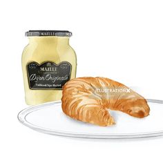 a croissant on a plate next to a jar of mustard