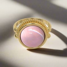 This stately ring is quintessentially classic in design, and is based on several Roman examples dating to the first and second centuries AD found in Bay of Naples towns, and in areas that were at one point known as Roman Britain. Its focal point is a prominent round stone in a bezel setting, which is crowned by a brilliant ribbed border. "Dignitas" was an important and serious concept in the Roman world - and something to which all Romans aspired - though it is difficult to define today. It mean Pink Round Heirloom Jewelry, Classic Adjustable Crystal Ring With Metal Band, Timeless Domed Cabochon Rings, Classic Adjustable Crystal Ring, Spiritual Open Ring With Polished Finish, Elegant Polished Opal Promise Ring, Elegant Domed Jewelry With Bezel Setting, Elegant Opal Promise Ring With Polished Finish, Classic Domed Cabochon Ring