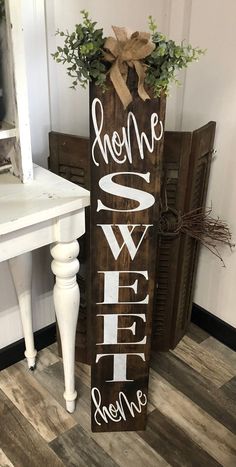 a wooden sign that says she me sweet and greenery on it next to a white table