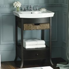 a white sink sitting under a bathroom mirror next to a wooden shelf filled with towels