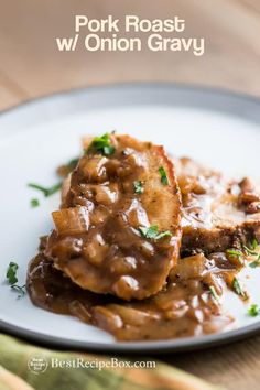 two pieces of meat covered in gravy on a white plate with parsley