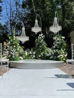 an outdoor ceremony setup with chandeliers and flowers