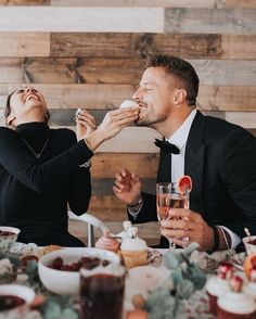 a man and woman sitting at a table eating cupcakes