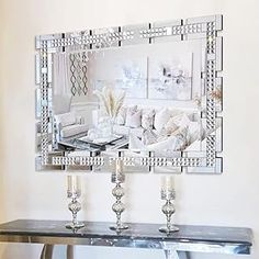 a mirrored table with candles on it in front of a couch and mirror above it