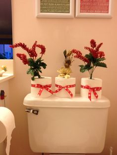 three toilet paper rolls with red bows on them are sitting on top of a white toilet