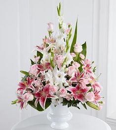 a white vase filled with pink and white flowers