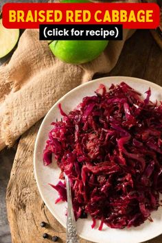 a white plate topped with red cabbage on top of a wooden cutting board next to an apple