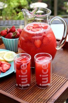 a pitcher of water with strawberries and lemons next to it on a tray