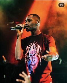 a man holding a microphone up to his mouth while standing in front of a crowd