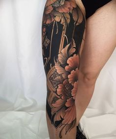 a woman's leg with flowers on it and a clock in the middle,