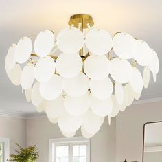 a chandelier hanging from the ceiling in a living room with white walls and furniture