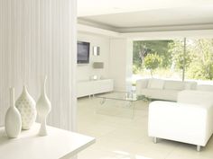 a white living room with three vases on the table and a television in the background