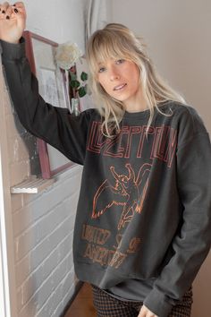 a woman standing in front of a brick wall with her hand up to the side