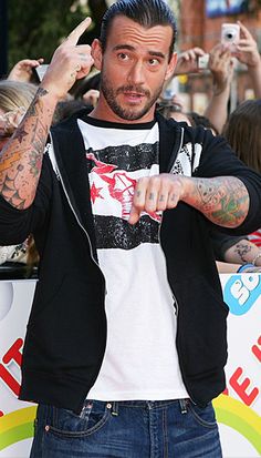 a man with tattooed arms and headphones in front of a large group of people