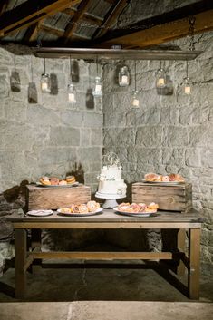 the table is set up with two cakes on it and mason jars hanging from the ceiling