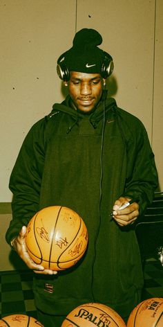 a young man holding a basketball and headphones