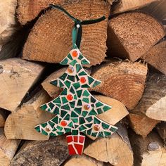 a christmas tree ornament is hanging from a pile of firewood in front of some logs