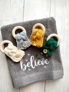 three knitted hair clips sitting on top of a gray towel with the word believe