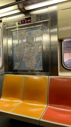 an empty subway car with two seats and a map on the wall behind it,